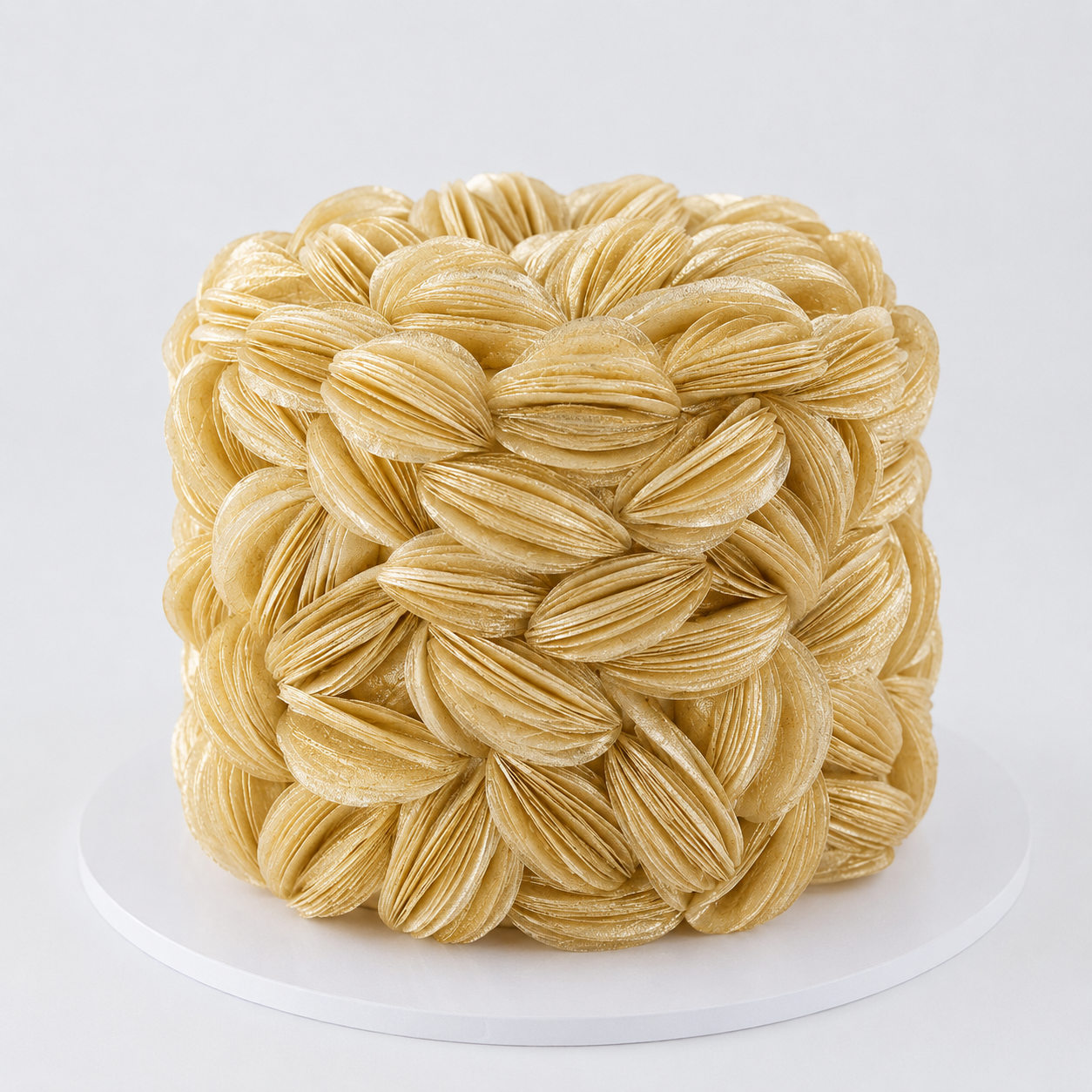 Luxury light gold wafer paper petal statement cake with textured floral wafer paper design on a white cake board