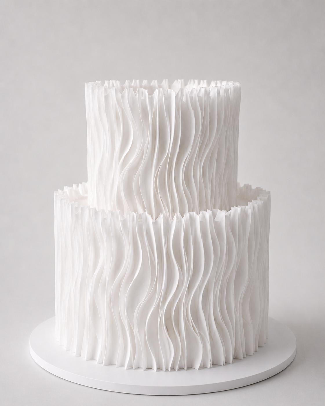 Luxury two-tier white wafer paper ruffle cake on a white cake board